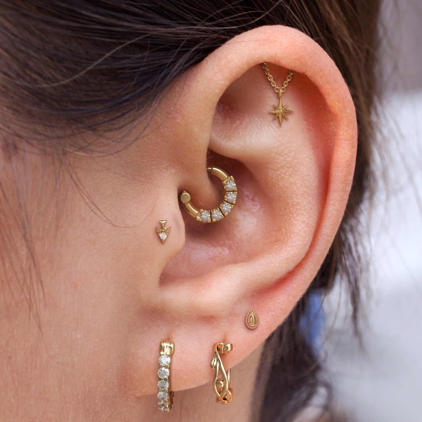 Close-up of an ear with multiple gold earrings
